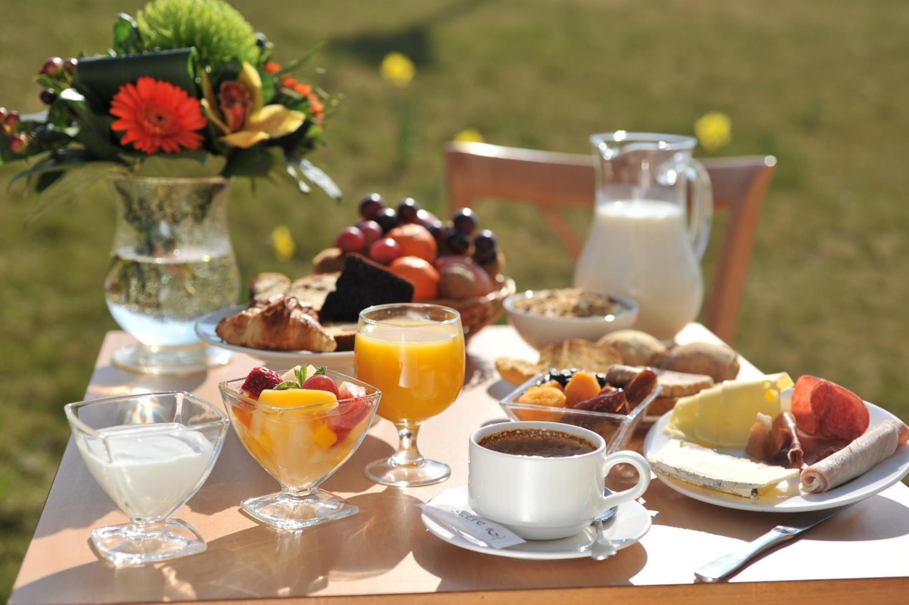 A breakfast table with various food items, including fruits, pastries, and beverages.