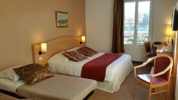 A hotel room with two beds, a desk with a chair, a TV, and a window with curtains.