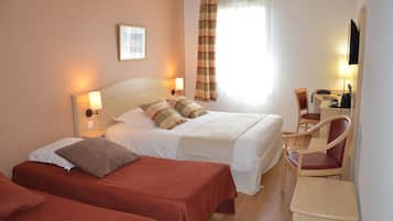 Une chambre d’hôtel avec deux lits, un bureau, une chaise et un téléviseur.
