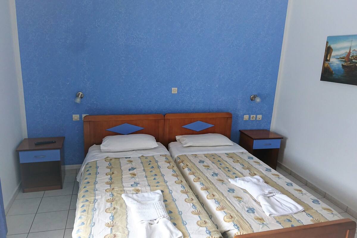 Una cama doble con una colcha estampada, dos mesitas de noche y un cuadro colgado en la pared.