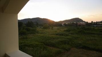 A view from a balcony overlooking a grassy field with hills in the distance.