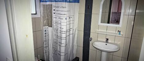 A bathroom with a shower curtain, a sink, and a mirror.