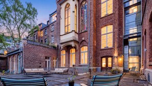 A courtyard with outdoor seating, brick buildings, and large windows. - Hopper Hotel St. Josef, WorldHotels Crafted (Cologne)