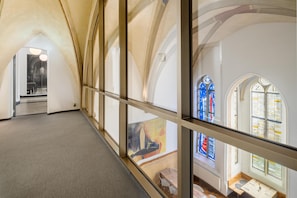 A corridor with arched ceilings and large windows with stained glass.