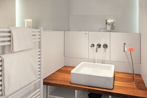 A bathroom with a white sink, a wooden countertop, a towel rack, and a vase with a flower. - Hopper Hotel St. Josef, WorldHotels Crafted (Cologne)