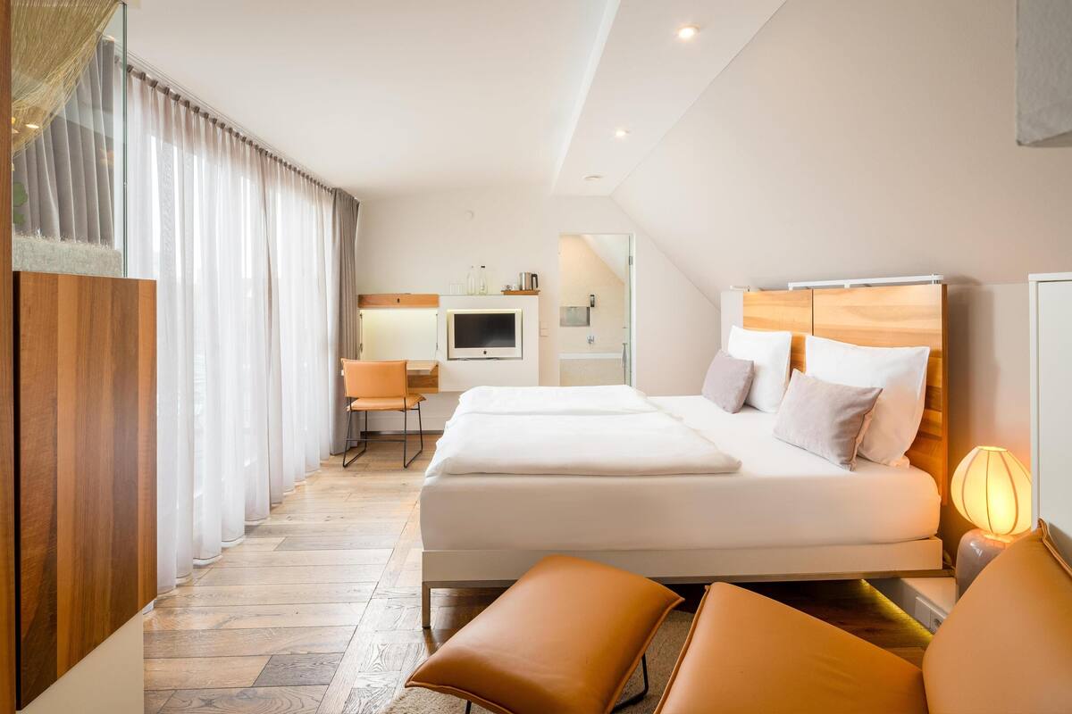 A hotel room with a bed, a desk, a TV, and a bathroom.