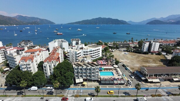 A coastal hotel with multiple buildings, a swimming pool, and a view of the sea with boats. - Reis Maris Hotel (Marmaris)