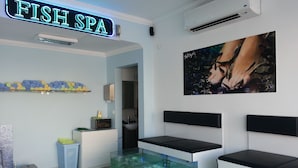 A room with a 'Fish Spa' sign, a large fish tank, a painting, and a microwave on a counter. - Reis Maris Hotel (Marmaris)
