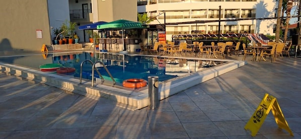 A swimming pool with lounge chairs and a bar area.