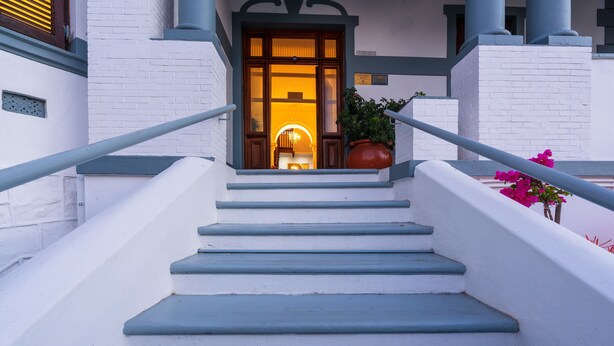 A staircase leading to a building entrance with a potted plant and flowers on the side. - Esperanza Guest House (Cape Town)