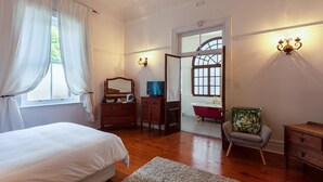 A bedroom with a bed, dresser, vanity, and a chair. - Esperanza Guest House (Cape Town)
