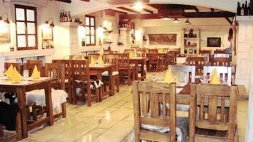 Un restaurante con mesas y sillas de madera, piso de baldosas y varias botellas en estanterías.