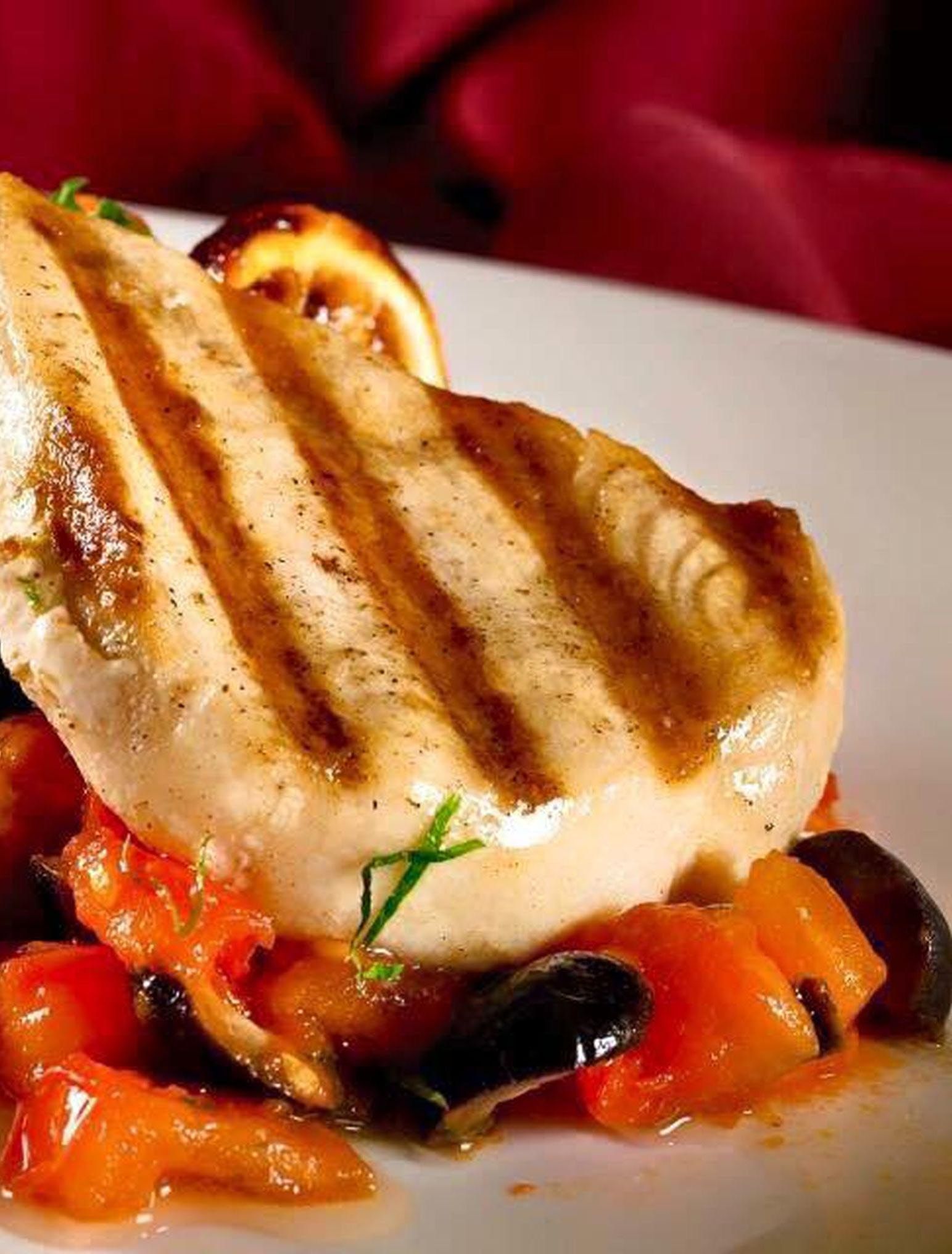 Une escalope de poulet grillée, accompagnée de légumes, présentée sur une assiette.