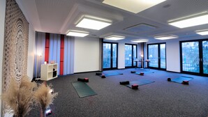 A spacious room with large windows, exercise mats, and a wall tapestry. - DJH City-Hostel Köln-Riehl (Cologne)