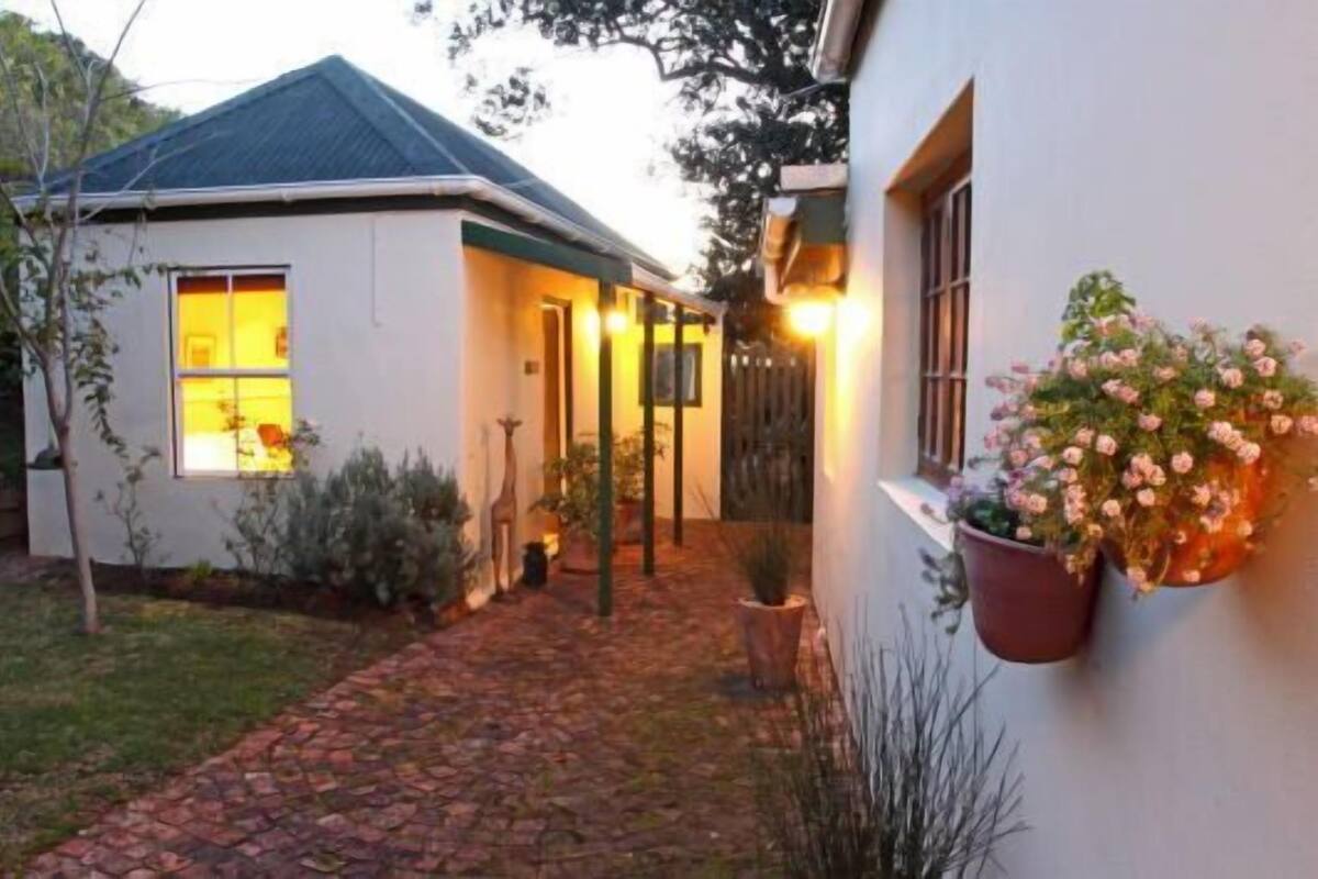 A house with a paved driveway, a small garden, and a window with a light on.