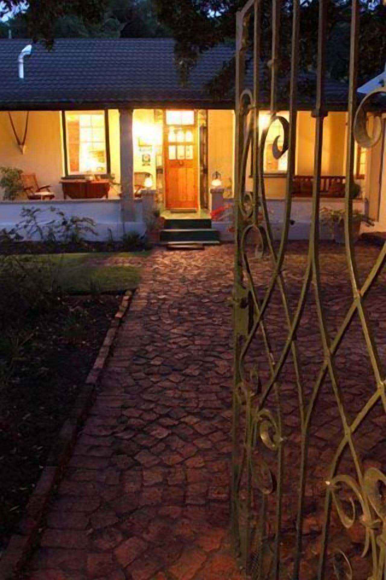 Una casa con un camino empedrado que lleva a la entrada, una puerta de madera y un interior bien iluminado.