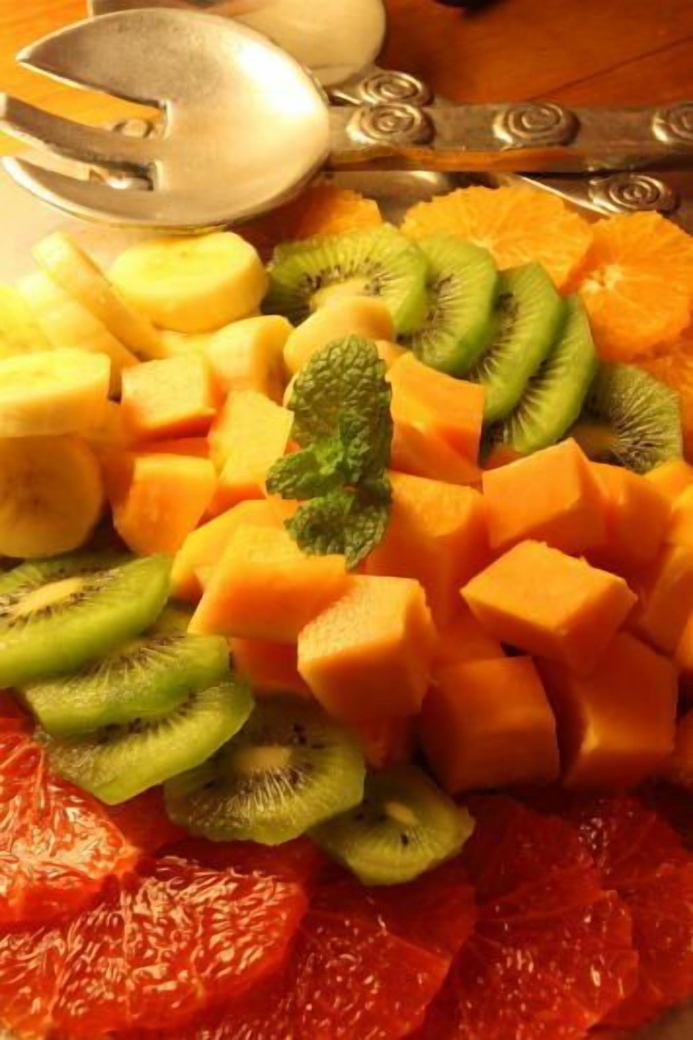 A fruit platter with various fruits including kiwi, mango, and orange slices.