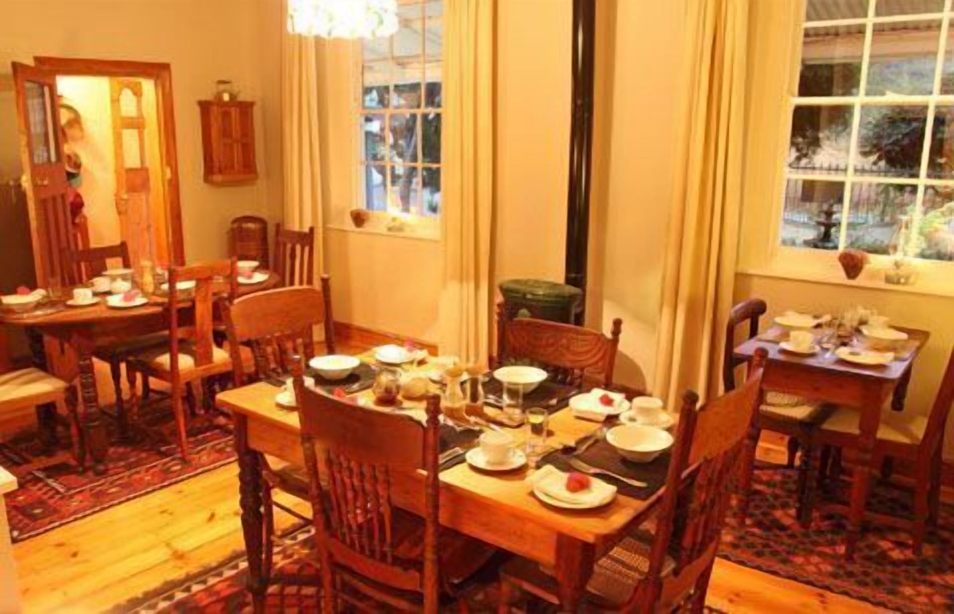 A dining room with a wooden table set for a meal, surrounded by chairs.