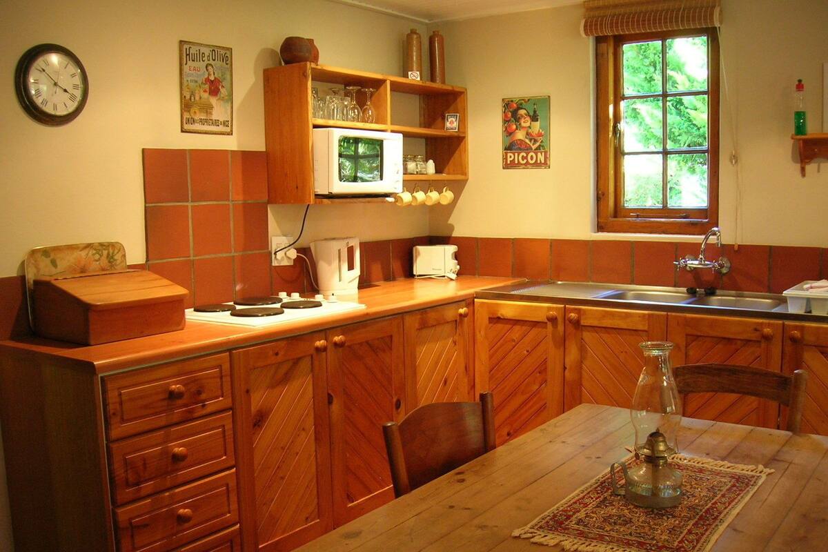 A kitchen with wooden cabinets, a microwave, a sink, and a dining table with chairs.