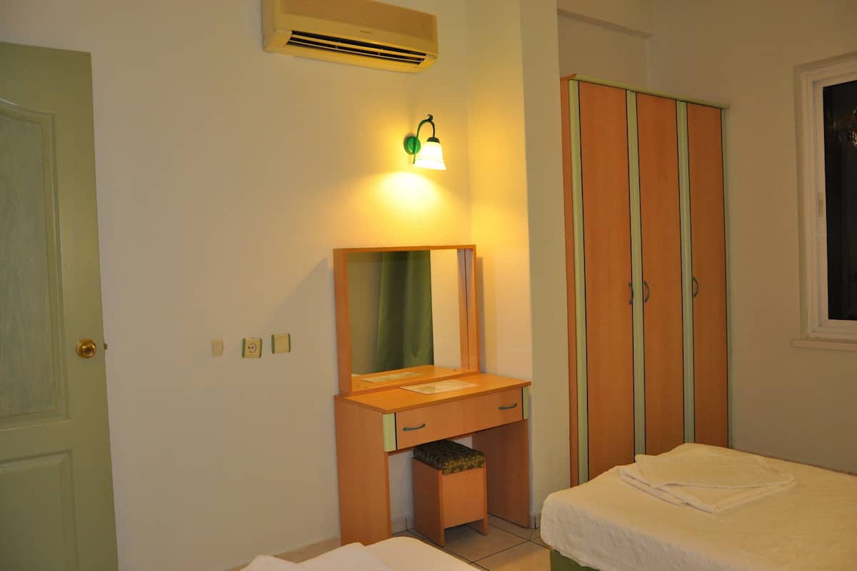 A bedroom with a wooden desk, a mirror, a wardrobe, and a bed.