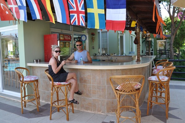 A bar area with wicker chairs, a counter, and flags hanging above. - Park Mar Apart (Marmaris)