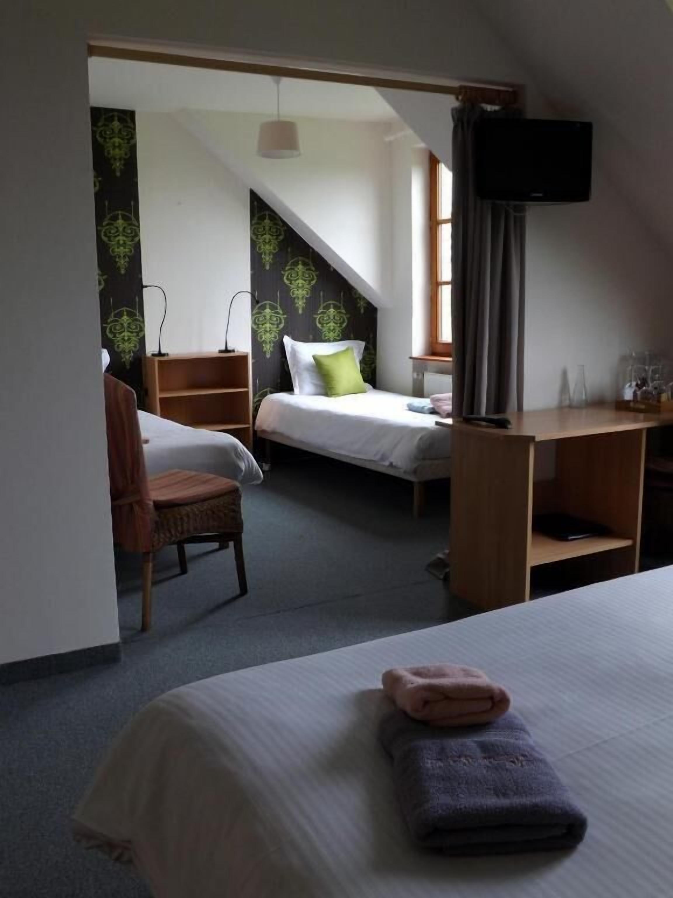 A hotel room with a bed, a desk, a chair, and a TV.