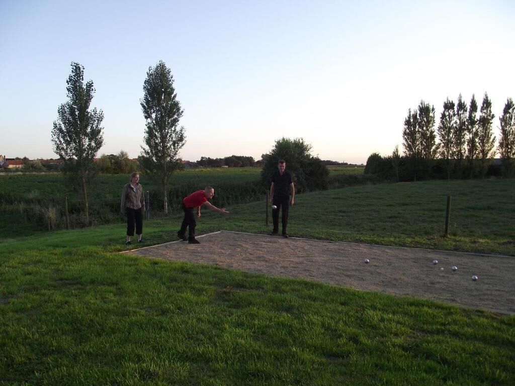 A group of people playing a game on a grassy field with trees in the background.