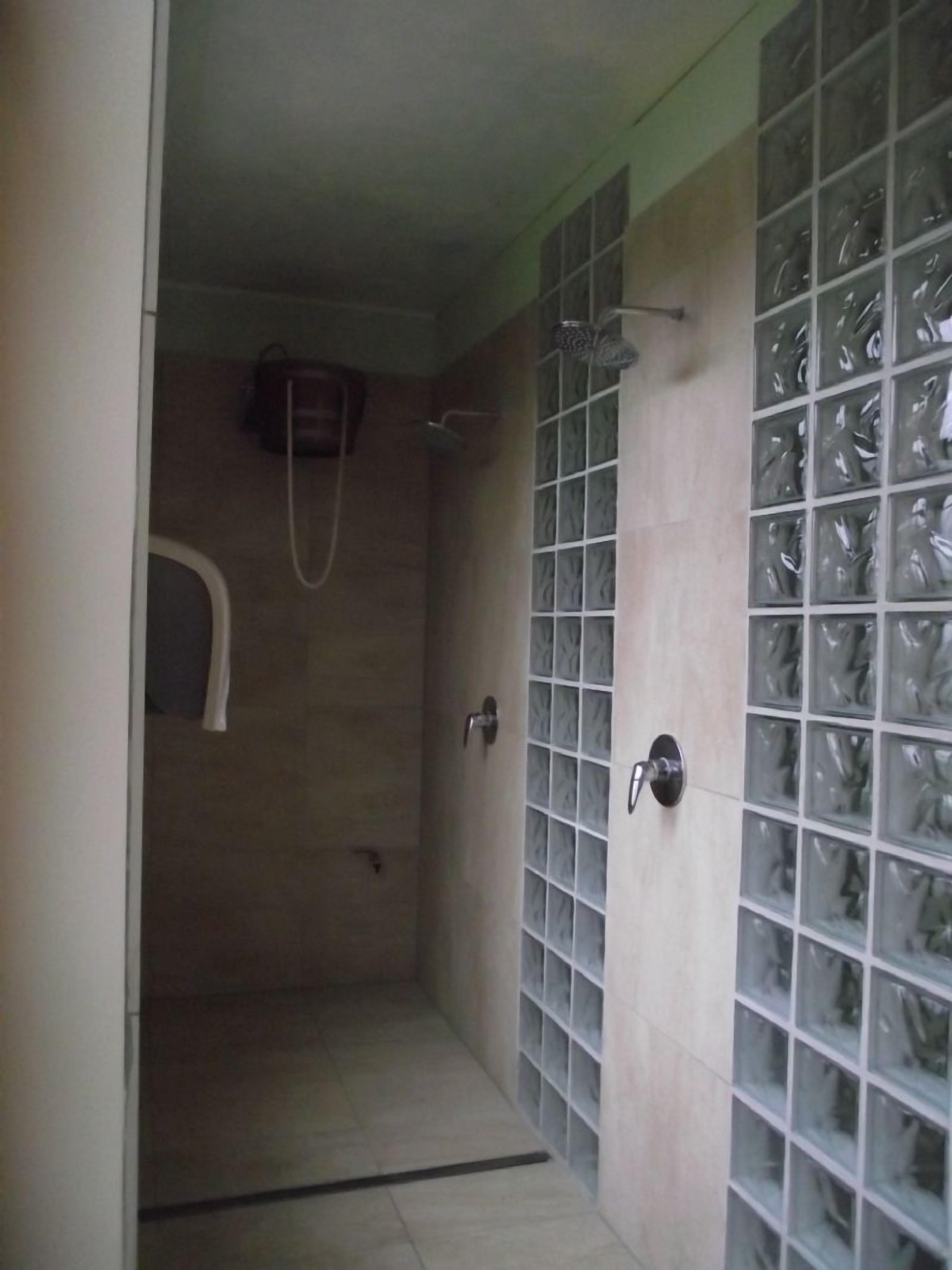 A small, enclosed shower area with a tiled floor and walls, a showerhead, and a towel rack.