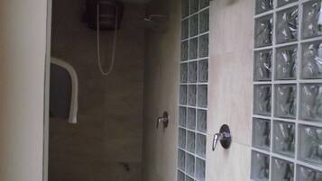 A small, enclosed shower area with a tiled floor and walls, a showerhead, and a towel rack.