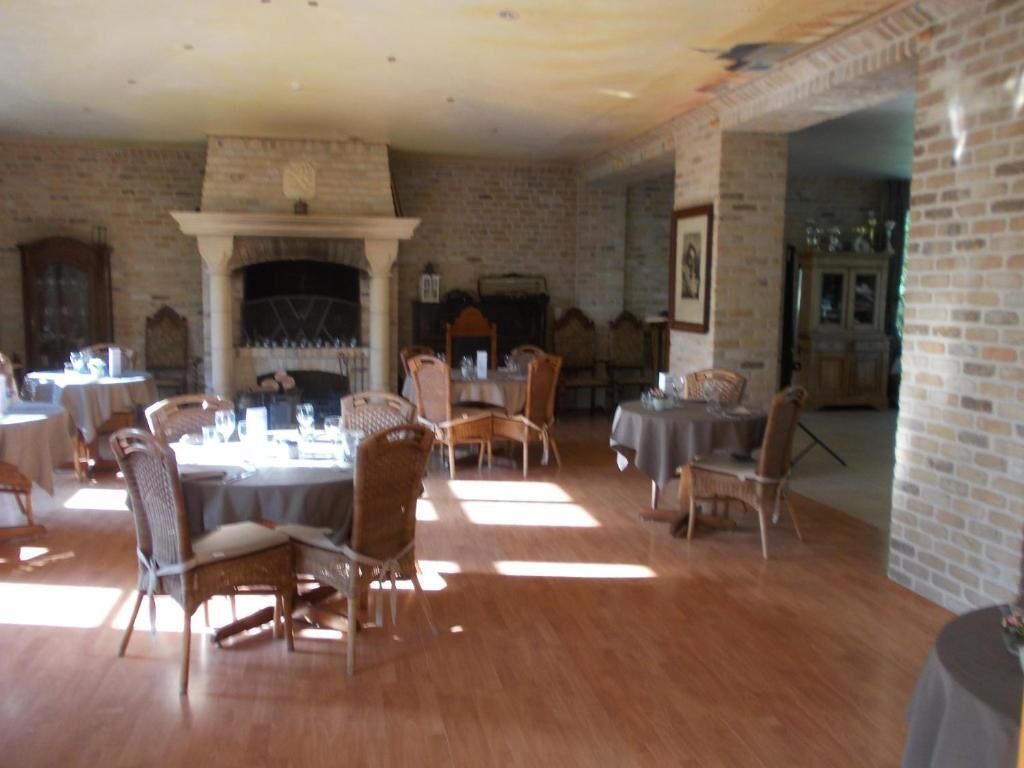 A dining room with brick walls, a fireplace, and wooden flooring.