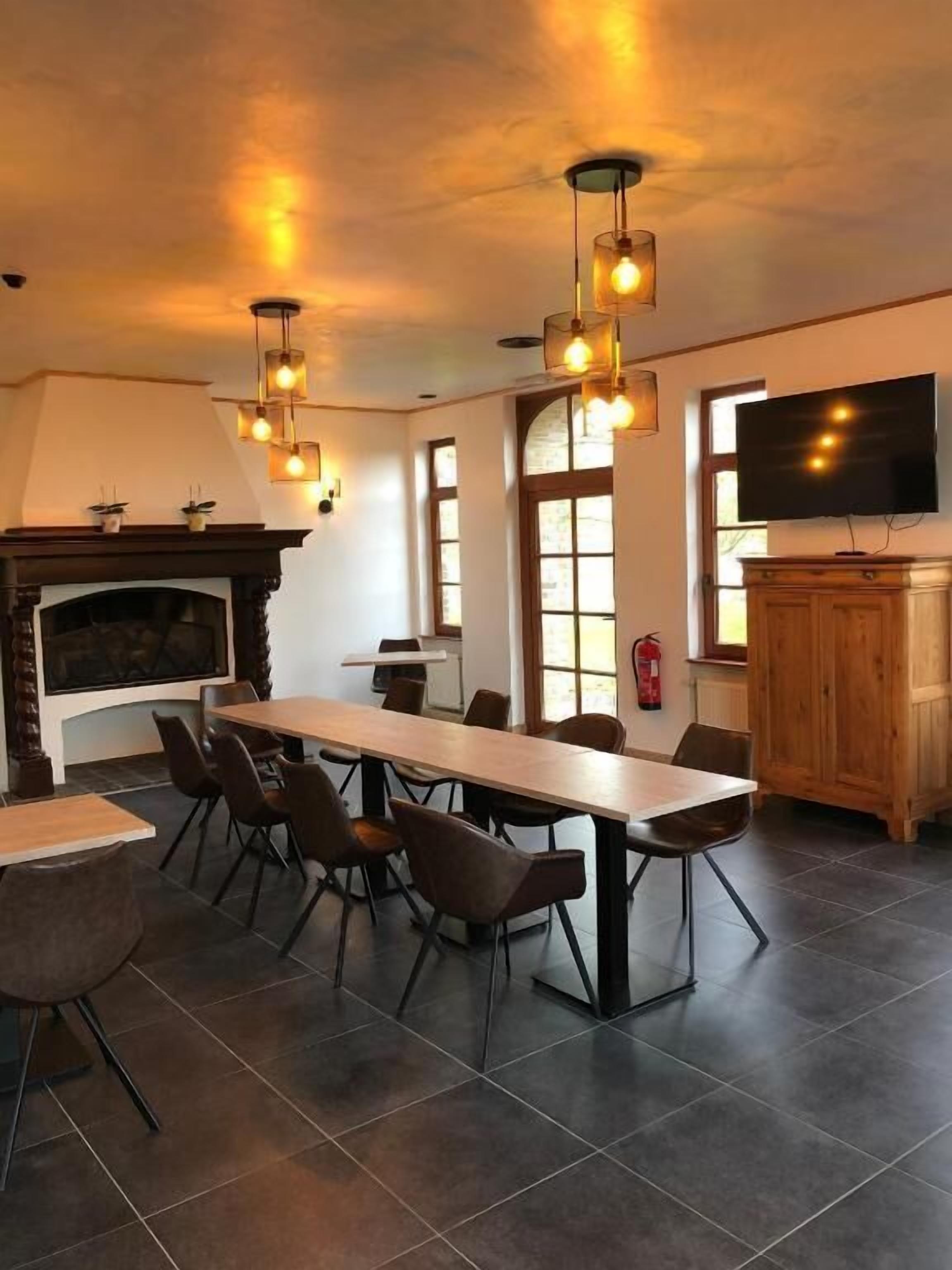 A dining area with a long table and chairs, a fireplace, and a television.