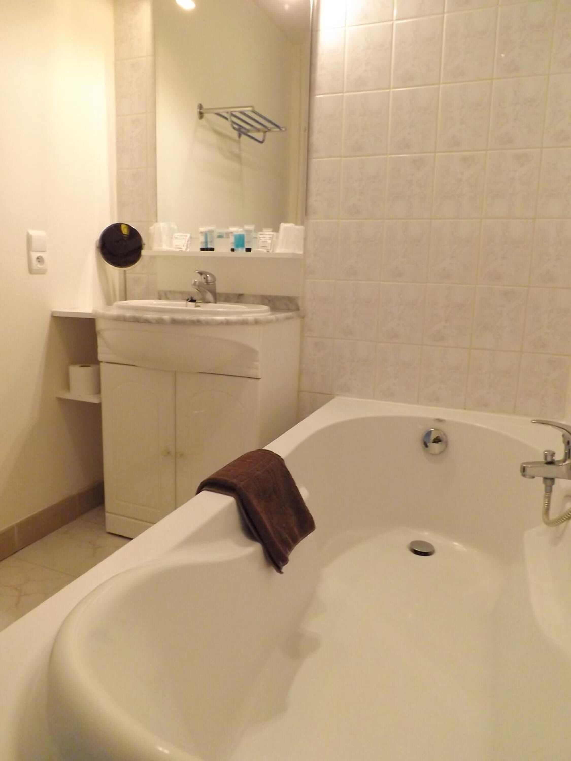 A bathroom with a bathtub, a sink, and a mirror.