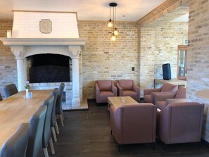 A room with a fireplace, seating area, and a dining table. - Hotel Hinterland (Alveringem)