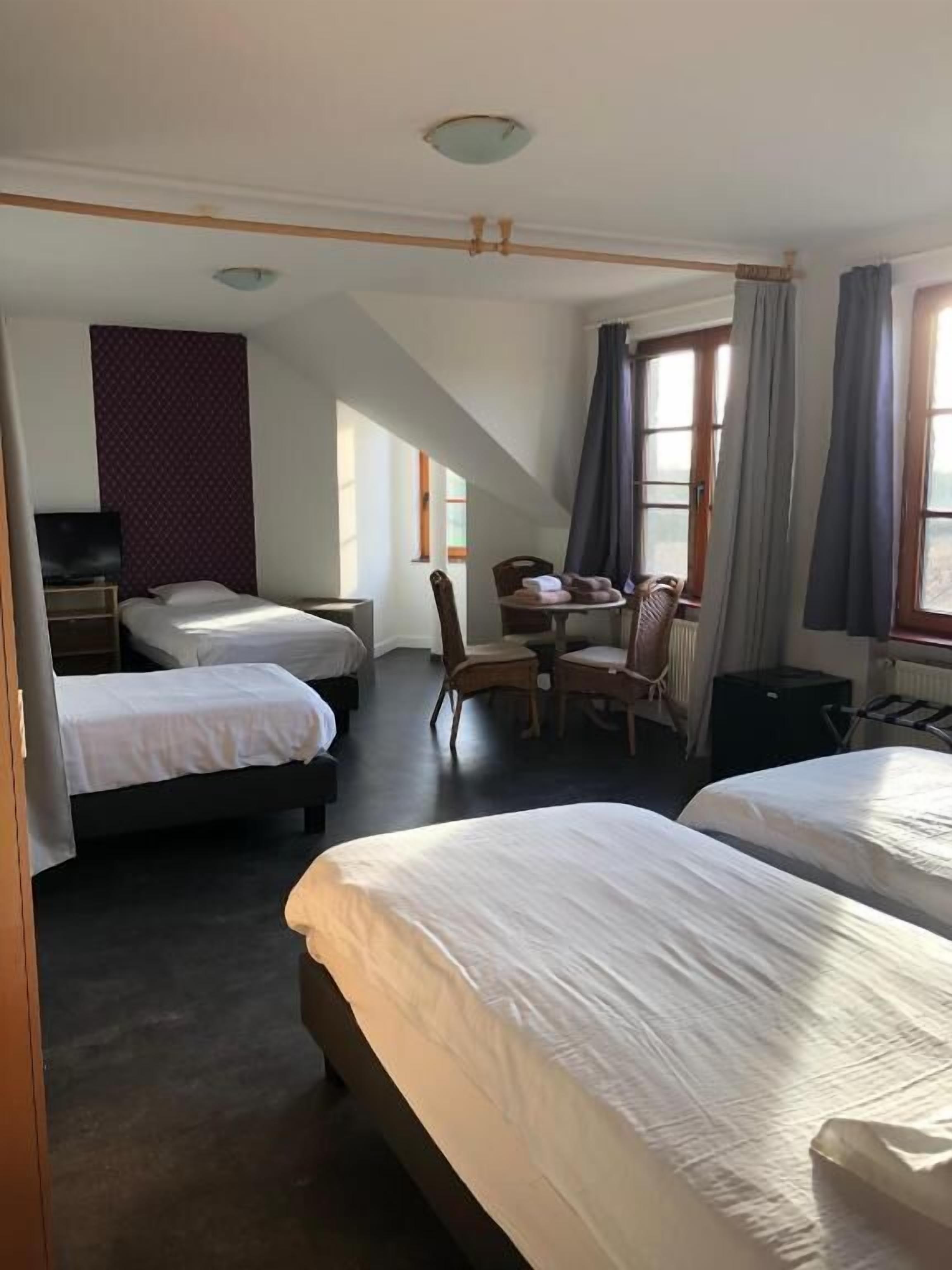 A hotel room with two beds, a desk, a chair, and a television.