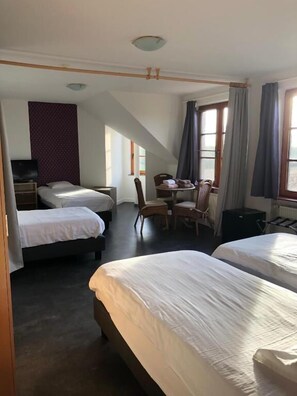 A hotel room with two beds, a desk, a chair, and a television.