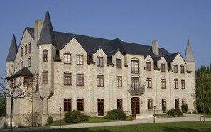A large, historic stone building with multiple towers and arched windows, featuring a symmetrical facade and a central entrance.