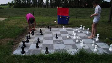 A chessboard set up outdoors with a red container and a blue container in the background.