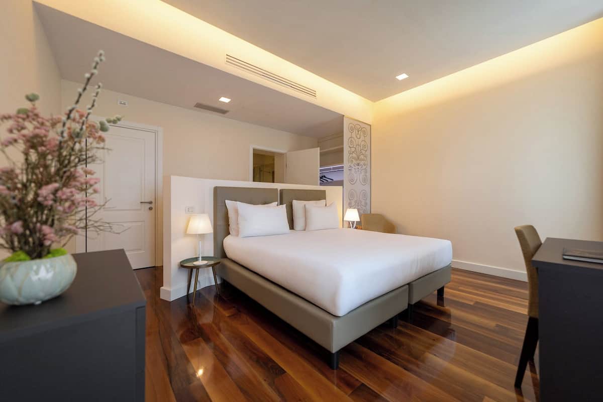 A modern hotel room with a large bed, bedside tables, a desk, and a chair.