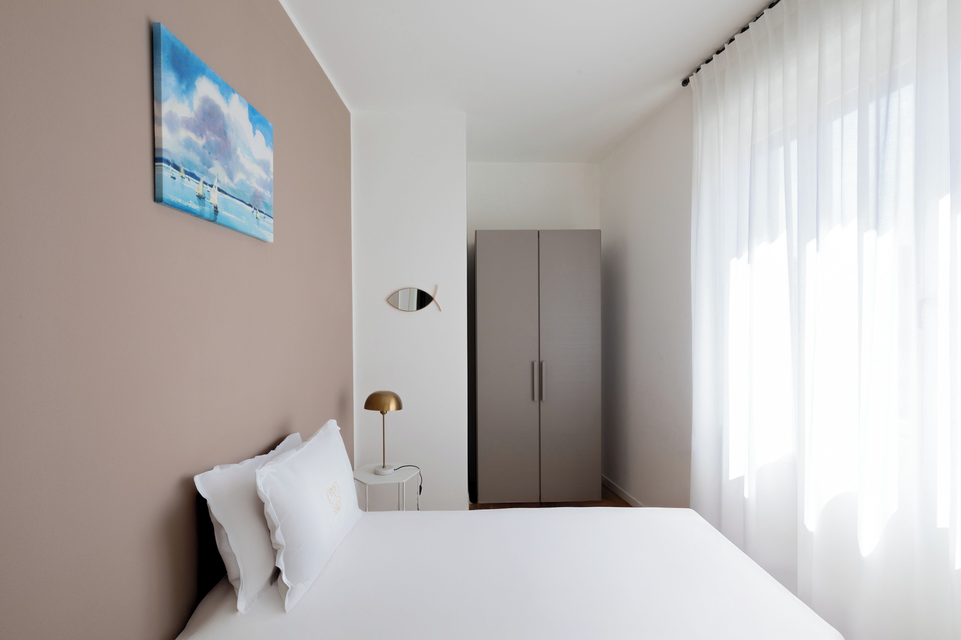 A bedroom with a bed, a nightstand, a lamp, a wardrobe, and a painting on the wall.