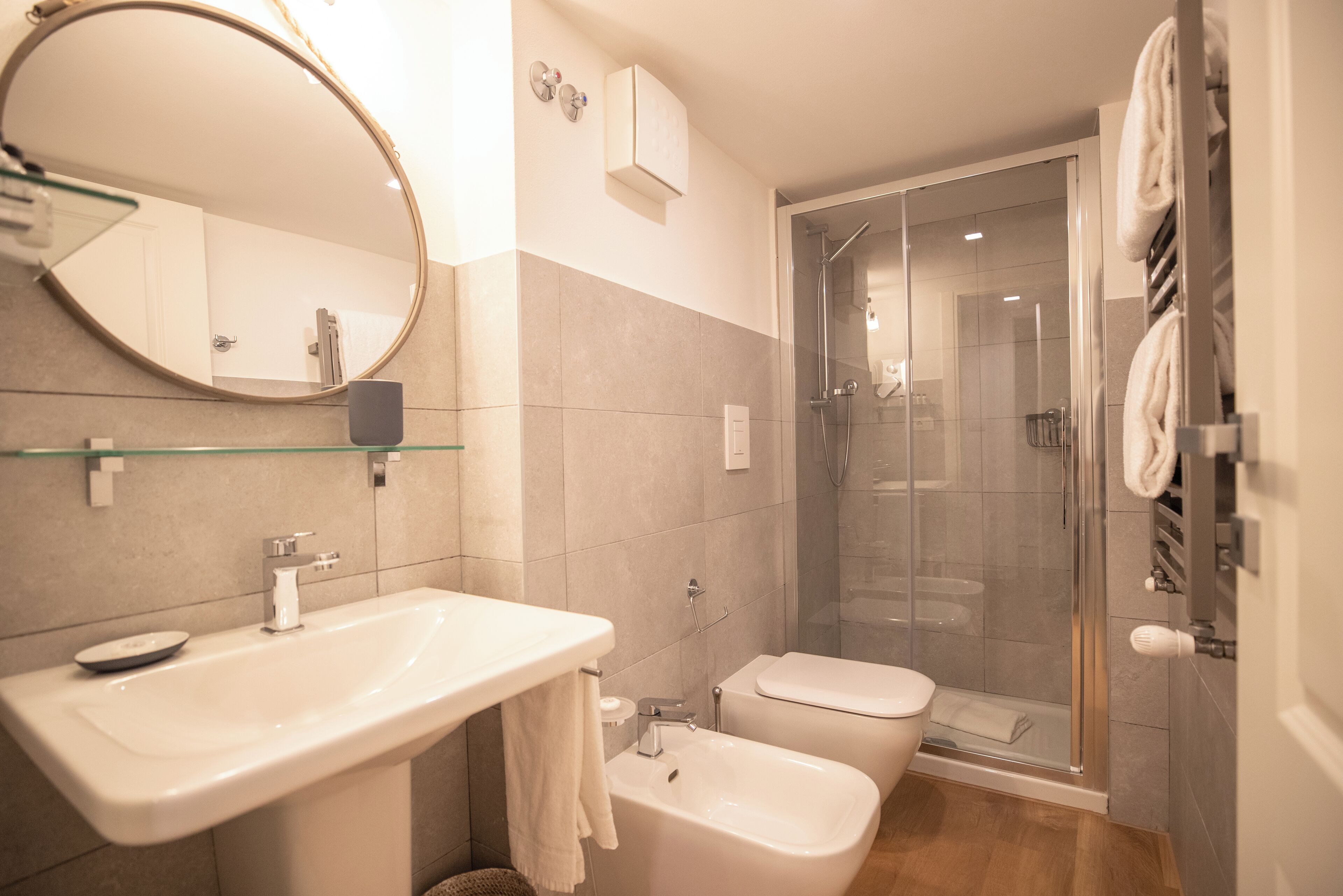 A modern bathroom with a glass shower enclosure, a white sink, and a toilet.