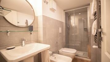 A modern bathroom with a glass shower enclosure, a white sink, and a toilet.