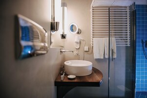 Un bagno moderno con un lavandino rotondo, un asciugacapelli, uno specchio e un porta asciugamani.