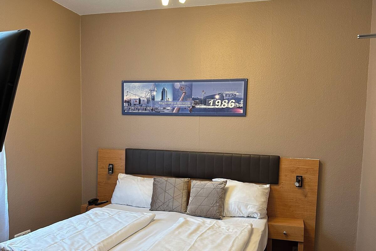 A neatly made double bed with a headboard, two bedside tables, and a ceiling light fixture.
