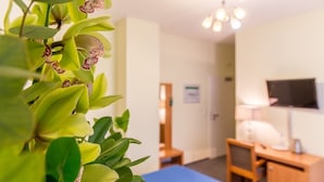 A hotel room with a bed, bedside table, lamp, and a television on the wall. - Hotel Expo Frankfurt City Centre - Digital Check-In (Frankfurt)