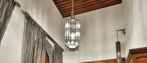 A traditional Moroccan interior with a checkered floor, wooden furniture, and a hanging chandelier.