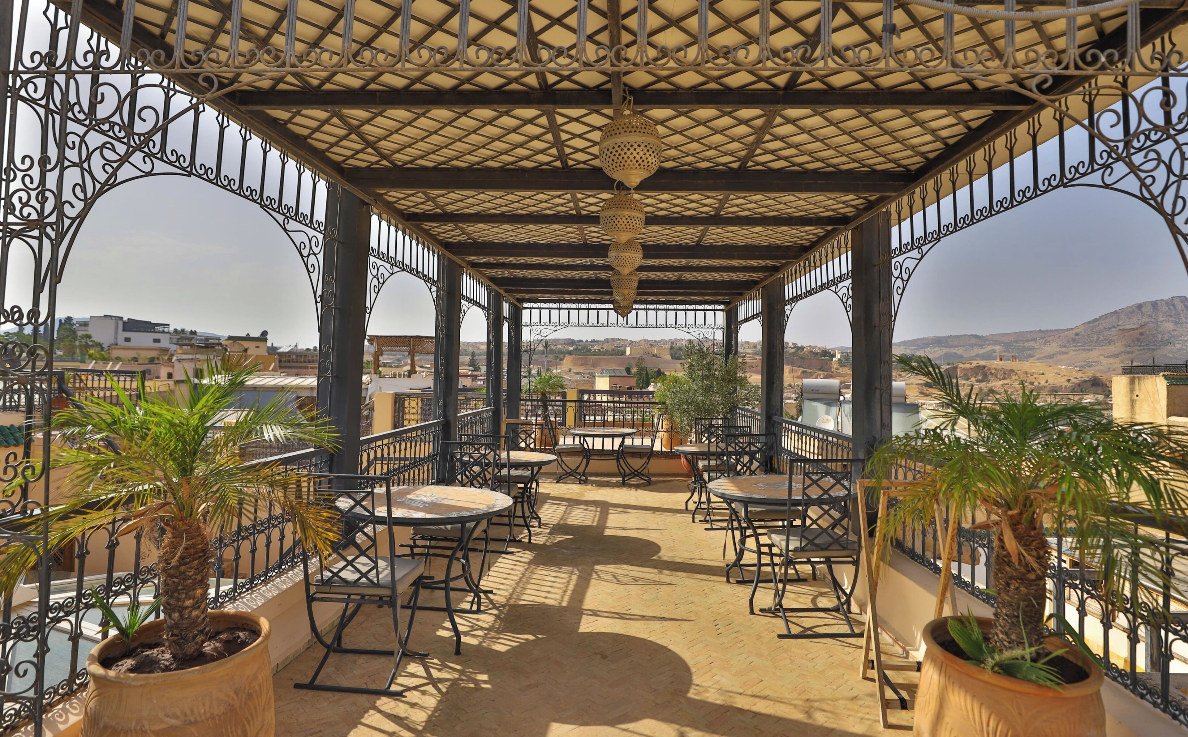 Terraza exterior con pérgola, zona de estar y plantas en macetas.