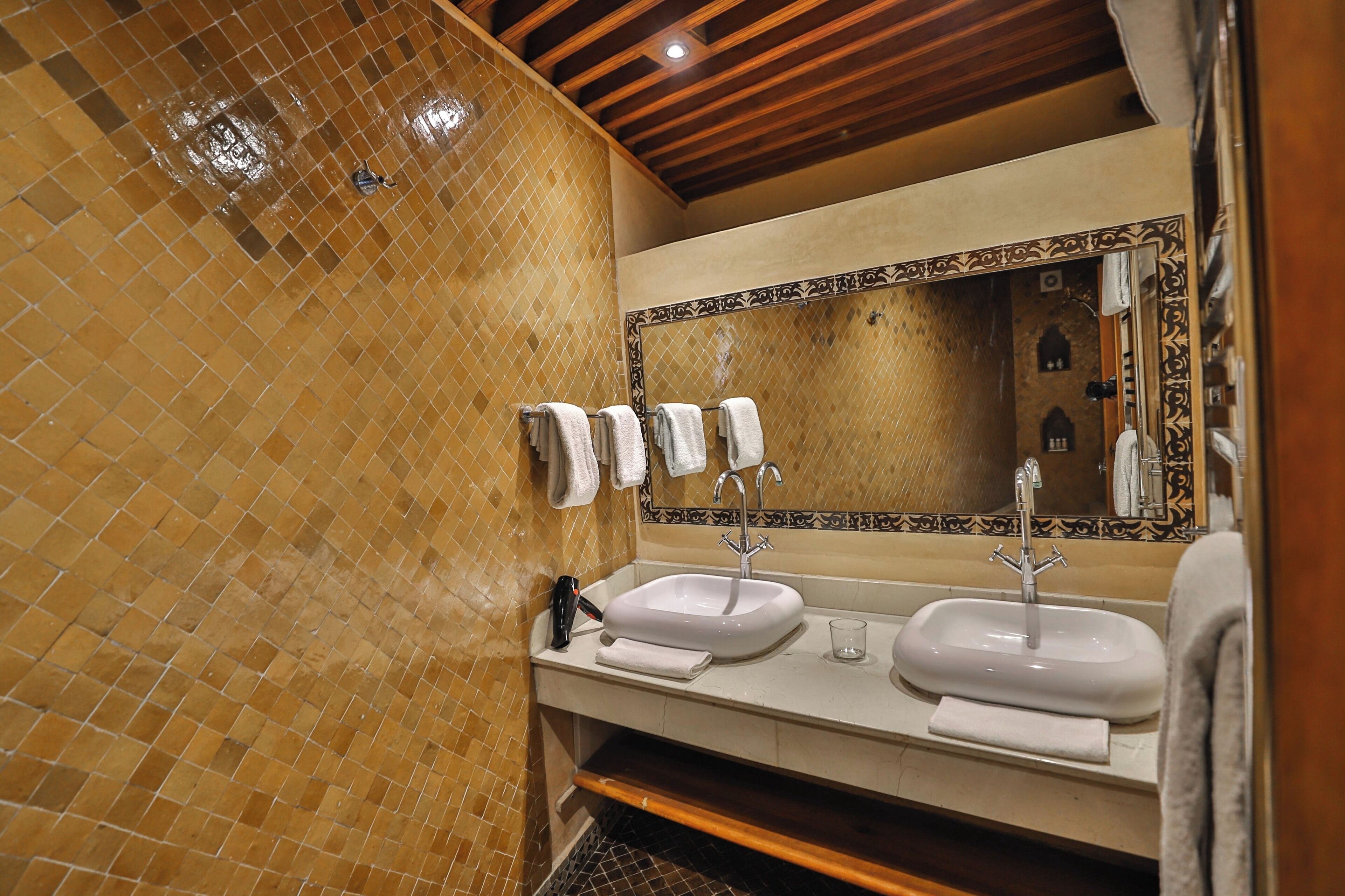A bathroom with two sinks, a large mirror, and tiled walls.