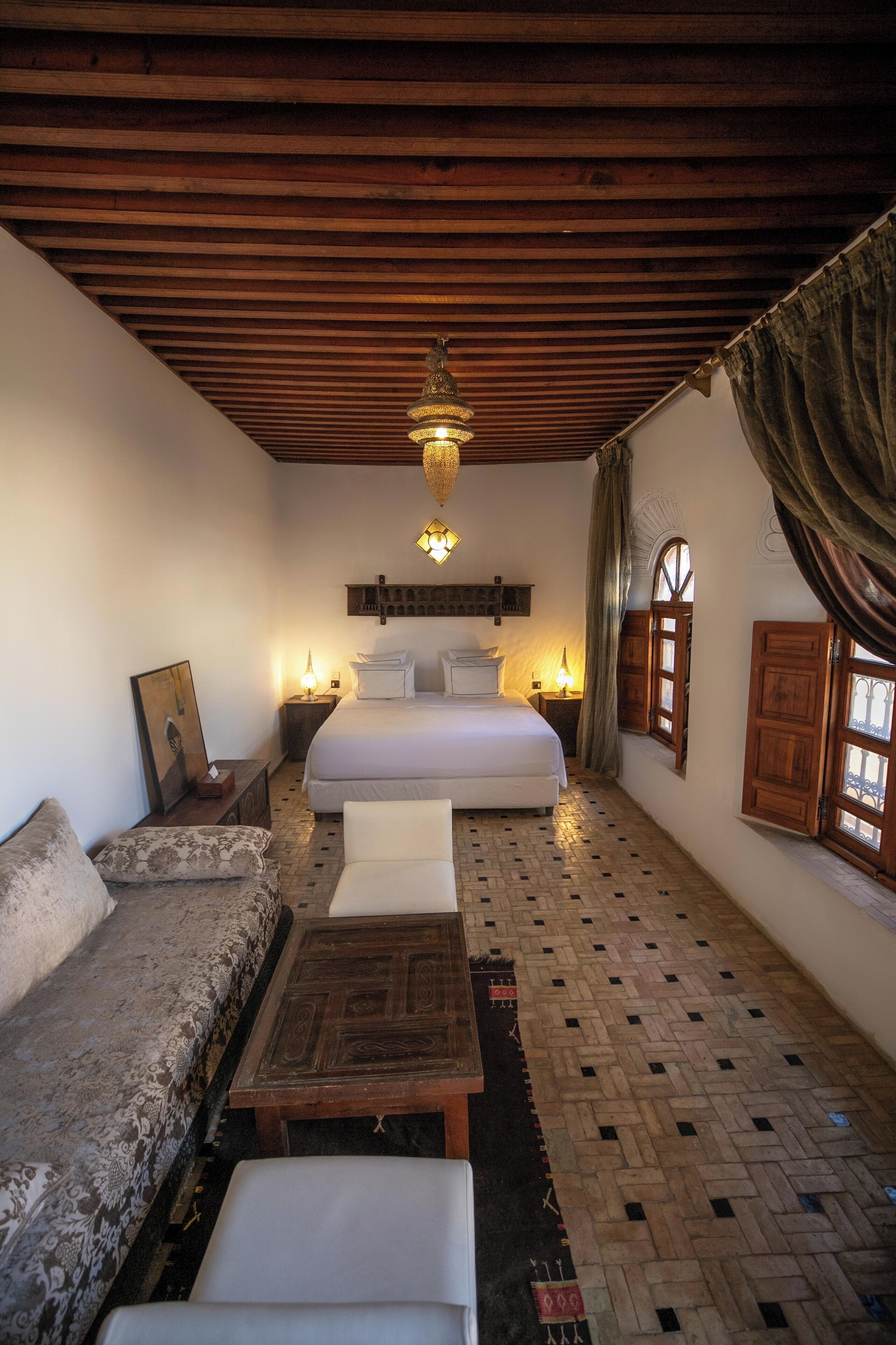 Una habitación acogedora con una cama, un sofá, una mesa de centro de madera y un tapete estampado.