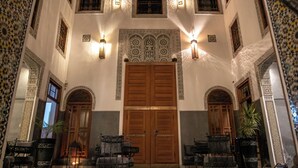 A spacious lobby with a checkered floor, large wooden doors, and traditional Moroccan decor. - Riad Layla (Fes)