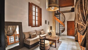 A spacious living area with a wooden staircase, a sofa set, and a dining table. - Riad Layla (Fes)